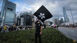 A protester waves a "Black Bauhinia" flag as others set up barricades at Lung Wo road outside the Legislative Council in Hong Kong before the flag raising ceremony to mark the 22nd anniversary of handover to China early on July 1, 2019. 