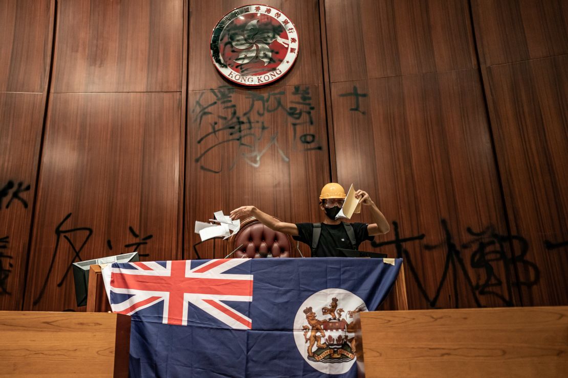 A protester inside the legislative chamber after the emblem had been defaced and the Hong Kong colonial flag draped over a podium.
