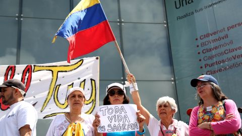 Venezuelans wave flags and hold signs at a demonstration called by opposition leader Juan Guaidó. The motto of the protest is "No more torture."