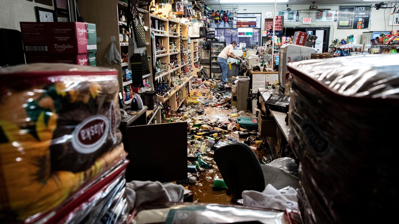 An employee stands behind the counter amid fallen bottles at a gas station and liquor store in Ridgecrest, California, on July 6, 2019.