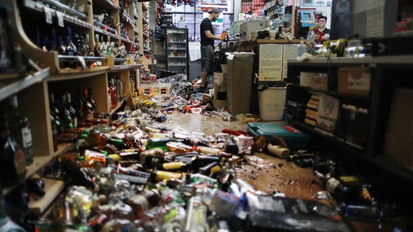 RIDGECREST, CALIFORNIA - JULY 06: An employee works at the cash register at Eastridge Market, near broken bottles scattered on the floor, following a 7.1 magnitude earthquake which struck in the area, on July 6, 2019 in Ridgecrest, California. The earthquake, which occurred July 5th, was the second large earthquake to hit the area in two days and the largest in Southern California in 20 years. The store has remained open since the 7.1 earthquake struck in an effort to serve the community. (Photo by Mario Tama/Getty Images)