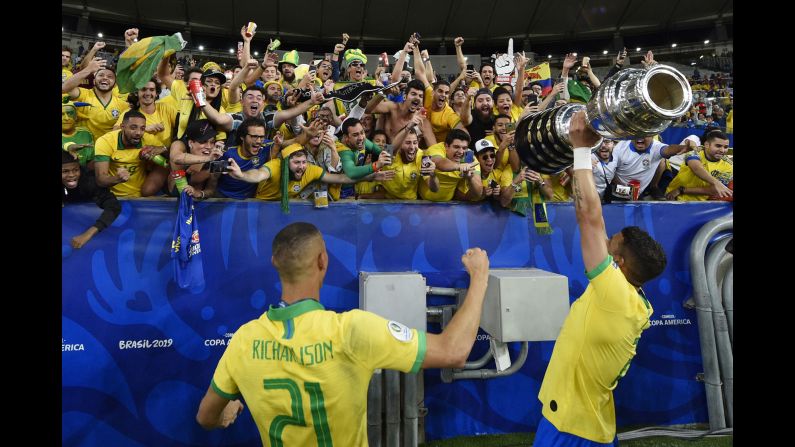 Brazil teammates Thiago Silva, right, and Richarlison display the Copa América trophy to supporters after defeating Peru in the final match at Maracana Stadium in Rio de Janeiro on Sunday, July 7.