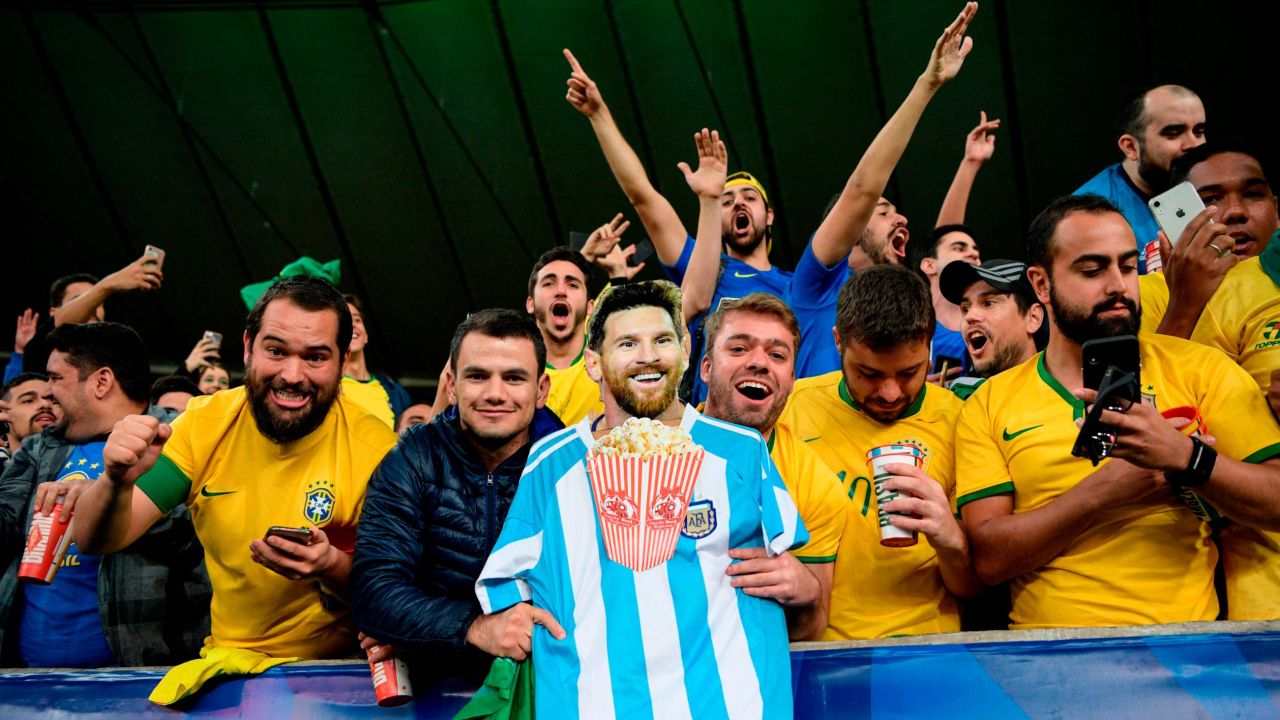 Fans of Brazil hold an image of Argentine footballer Lionel Messi eating popcorn as they celebrate. 