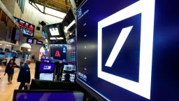 The logo for Deutsche Bank appears above a trading post on the floor of the New York Stock Exchange, Monday, July 8, 2019. Germany's struggling Deutsche Bank said Sunday it would cut 18,000 jobs by 2022, downsizing its volatile investment banking division in a restructuring aimed at restoring consistent profitability and better returns to shareholders. (AP Photo/Richard Drew)
