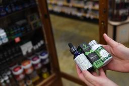 Sarah Shebanek, a wellness buyer for Alfalfa's, holds some of the CBD oil supplements sold in the Colorado store.