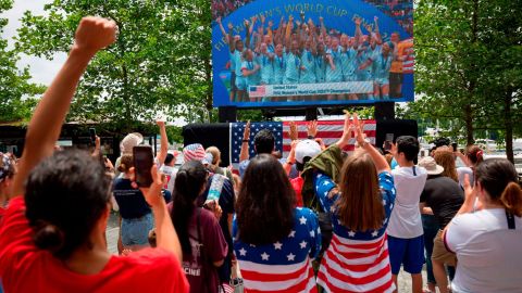 USA's players are seen on a screen celebrating, as fans watch the France 2019 Women's World Cup final football match.