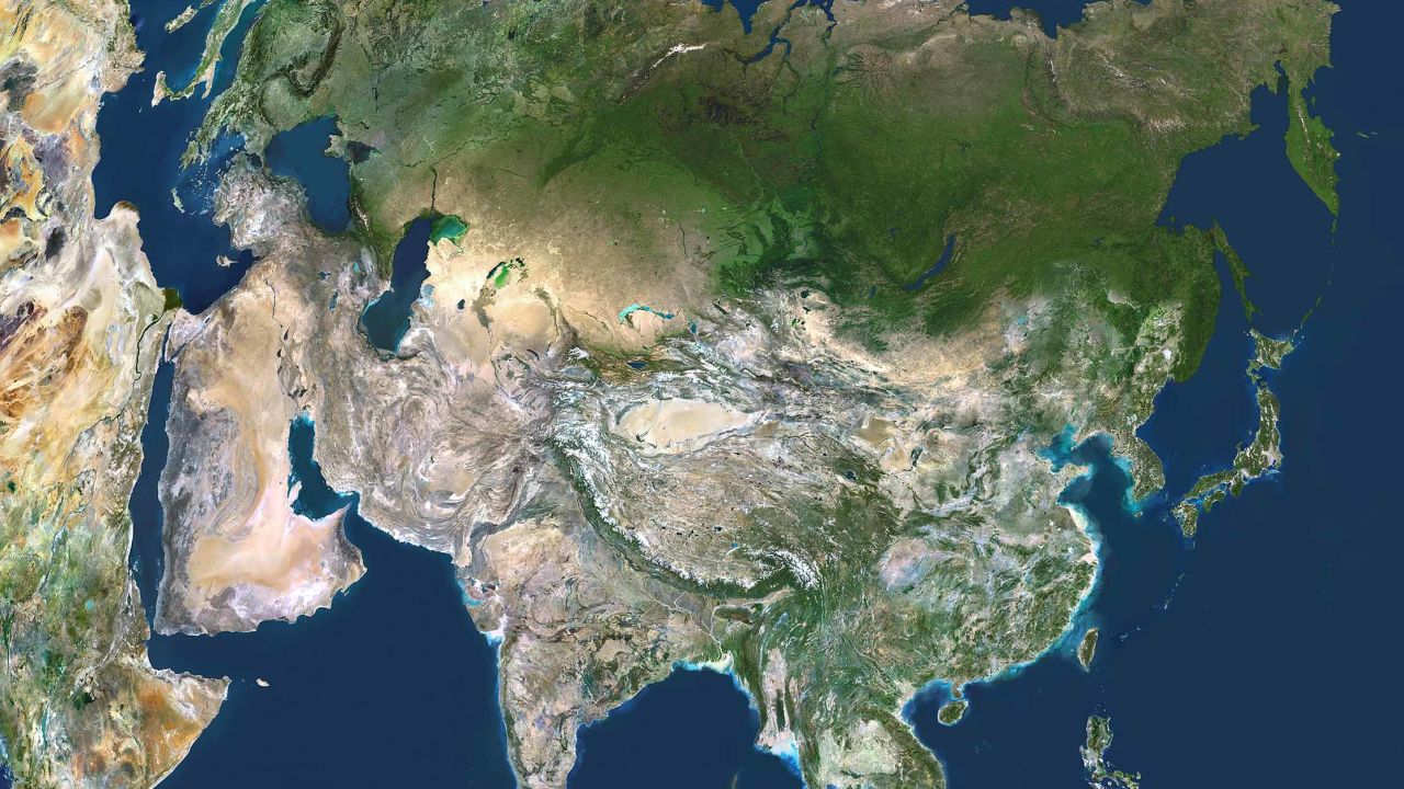 Asia. True colour satellite image centred on Asia, with nearly all of Africa (down left) and Europe (upper left) seen. This image shows the curvature of the Earth, with north-south lines converging towards top. The terrain of Asia varies from deserts (brown, central and southern Asia), to tropical rainforests (dark green, South-East Asia and the Malay Archipelago), to grasslands, forests and tundra (lighter green, northern Asia), and mountain ranges (centre). Also seen is the Arctic (top), Alaska (top right), and the Pacific Ocean (right) and Indian Ocean (lower left). The image used data from LANDSAT 5 & 7 satellites., Asia, True Colour Satellite Image (Photo by Planet Observer/Universal Images Group via Getty Images)