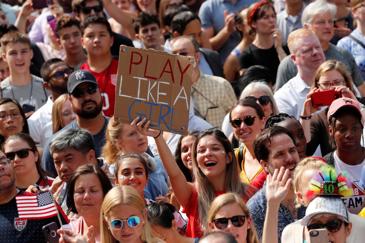A fan holds up a sign reading PLAY LIKE A GIRL.