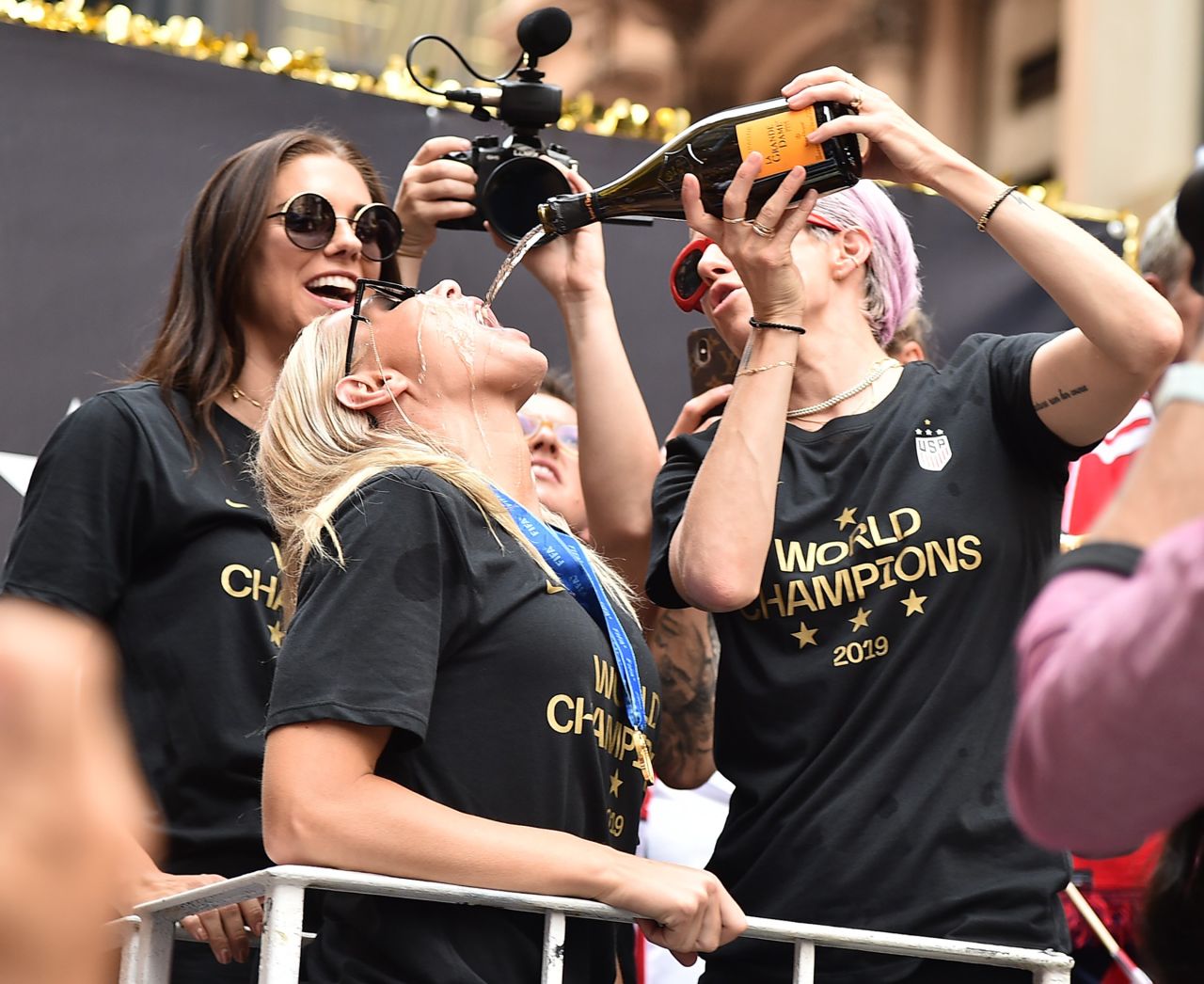 Alex Morgan, Allie Long and Megan Rapinoe celebrate with champagne. 