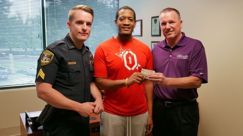 Randrell Lewis, center, turned in cash to Dunwoody Police Sgt. Robert Parsons, left, and Chief Billy Grogan.