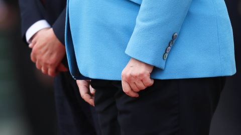 The hands of Merkel and Finnish Prime Minister Antti Rinne are seen as they listen to national anthems in Berlin in July 2019. Merkel's body <a href=