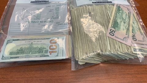 Cash that flew from the trucks is held by police in bags.