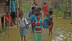 Rohingya children walking in the floodwater with their school bags going to their learning center. (July 7, 2019)
