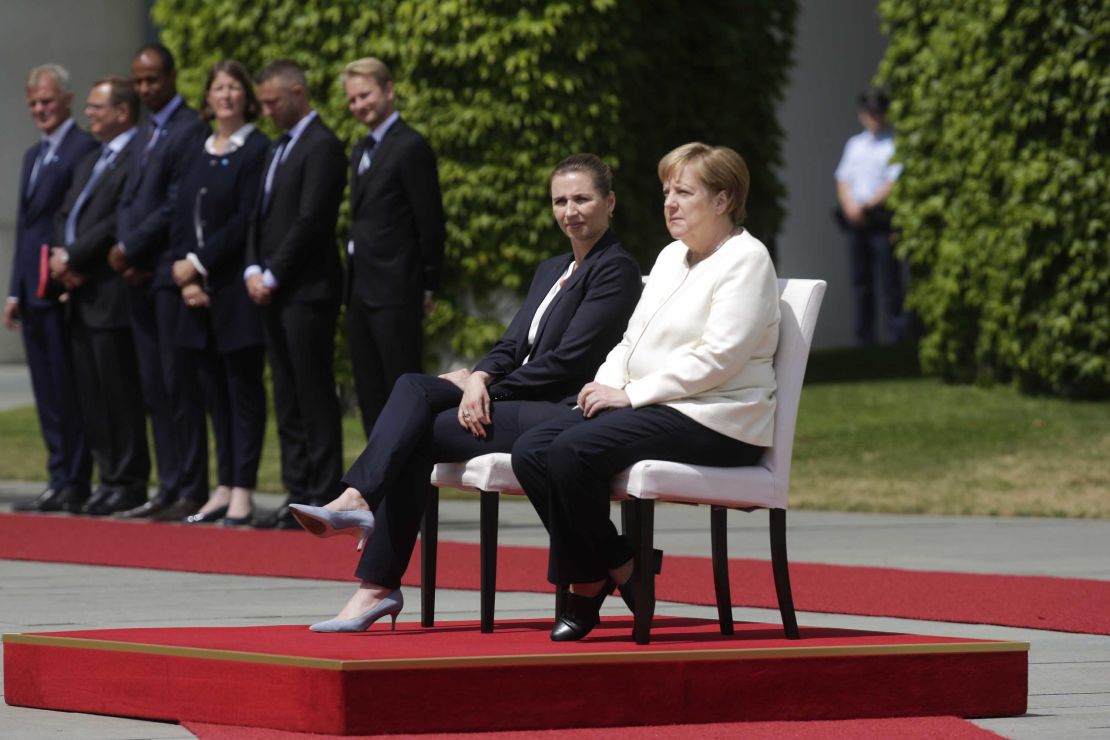 German Chancellor Angela Merkel, center right, and Danish Prime Minister Mette Frederiksen, sit on chairs as they listen to the national anthems on Thursday.