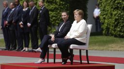 German Chancellor Angela Merkel, center right, and Danish Prime Minister Mette Frederiksen, center left, sit on chairs as they listen to the national anthems prior to a meeting at the chancellery in Berlin, Thursday, July 11, 2019. German Chancellor and the visiting Danish prime minister sit through their countries' national anthems at a ceremony in Berlin, a day after the latest of three incidents in which Merkel's body shook as she stood during the ceremony. (AP Photo/Markus Schreiber)