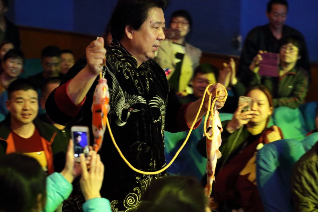 Audience members take pictures of Tian performing his carp illusion.  