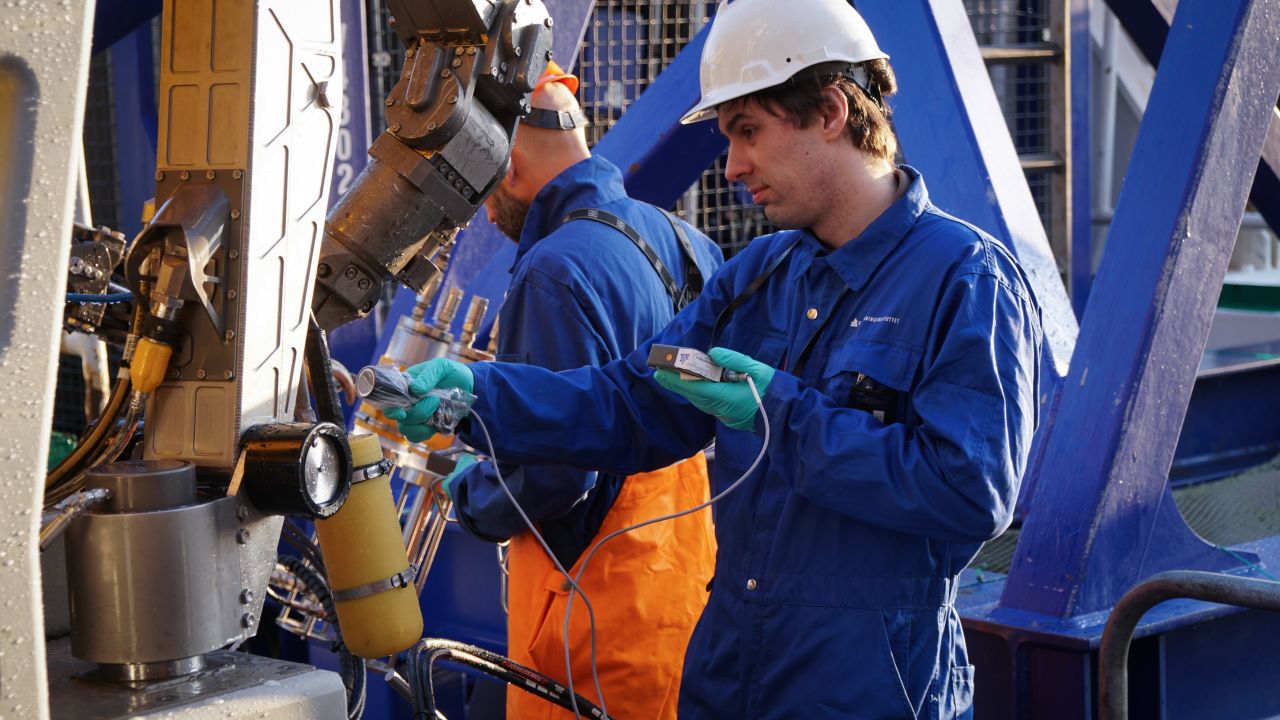Researchers Andrey Volynkin and Justin Gwynn carefully inspect their underwater robot.