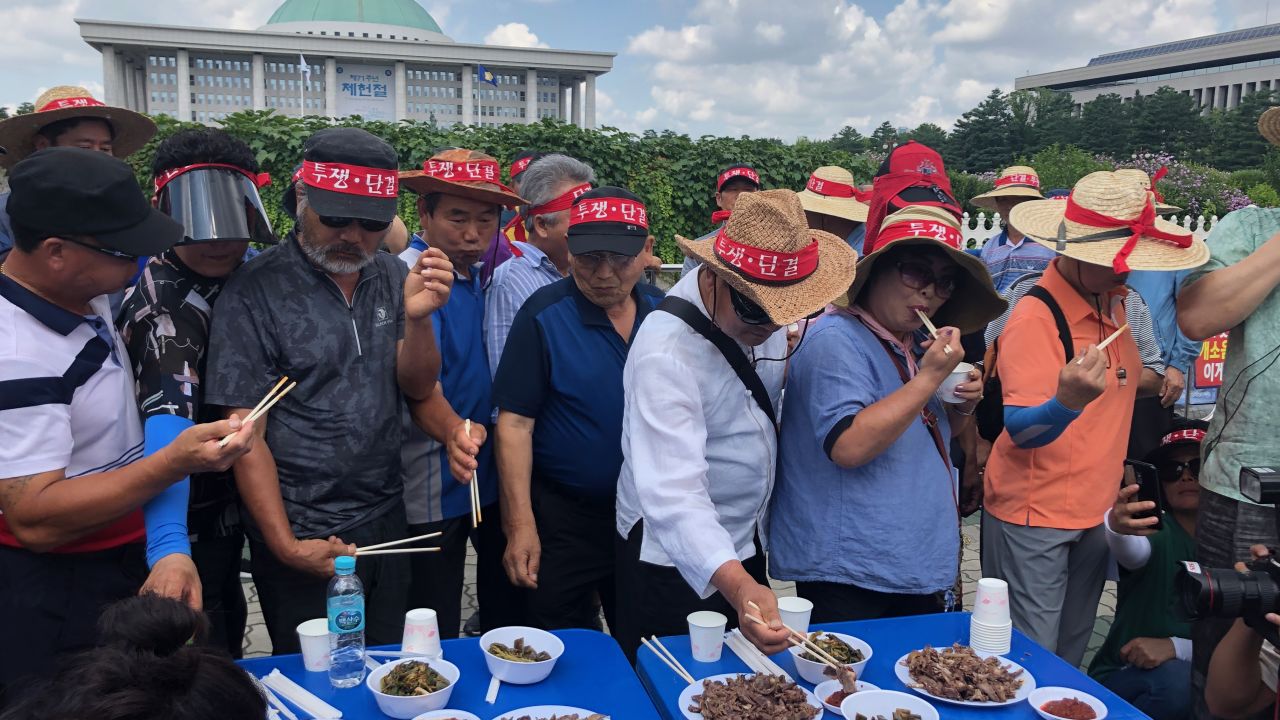 Members of the Korea Dog Farmers' Association eat dog meat in front of the National Assembly as part of their protest against putting ban on dog meat consumption.