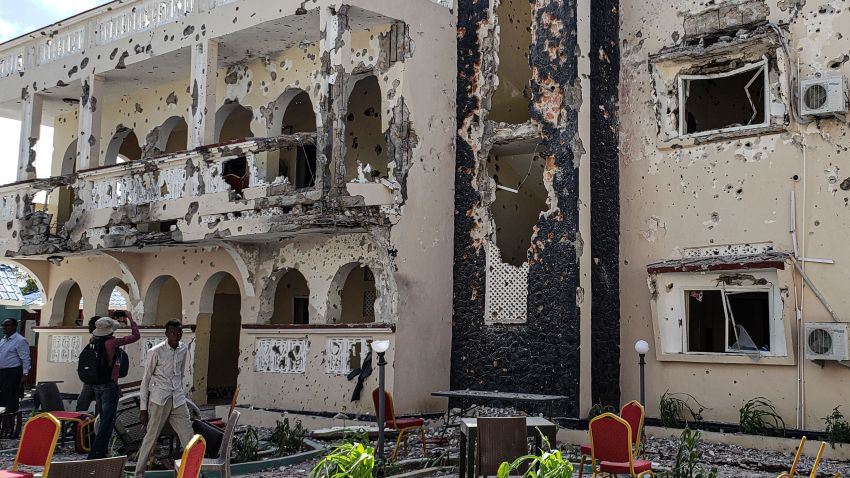 TOPSHOT - A man passes in front of the rubbles of the popular Medina hotel of Kismayo on July 13, 2019, a day after at least 26 people, including several foreigners, were killed and 56 injured in a suicide bomb and gun attack claimed by Al-Shabaab militants. - A suicide bomber rammed a vehicle loaded with explosives into the Medina hotel in the port town of Kismayo before several heavily armed gunmen forced their way inside, shooting as they went, authorities said. (Photo by STRINGER / AFP) (Photo credit should read STRINGER/AFP/Getty Images)