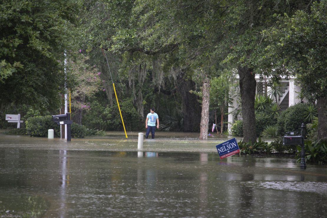 A man stands in flood water outside a home near Lake Pontchartrain.