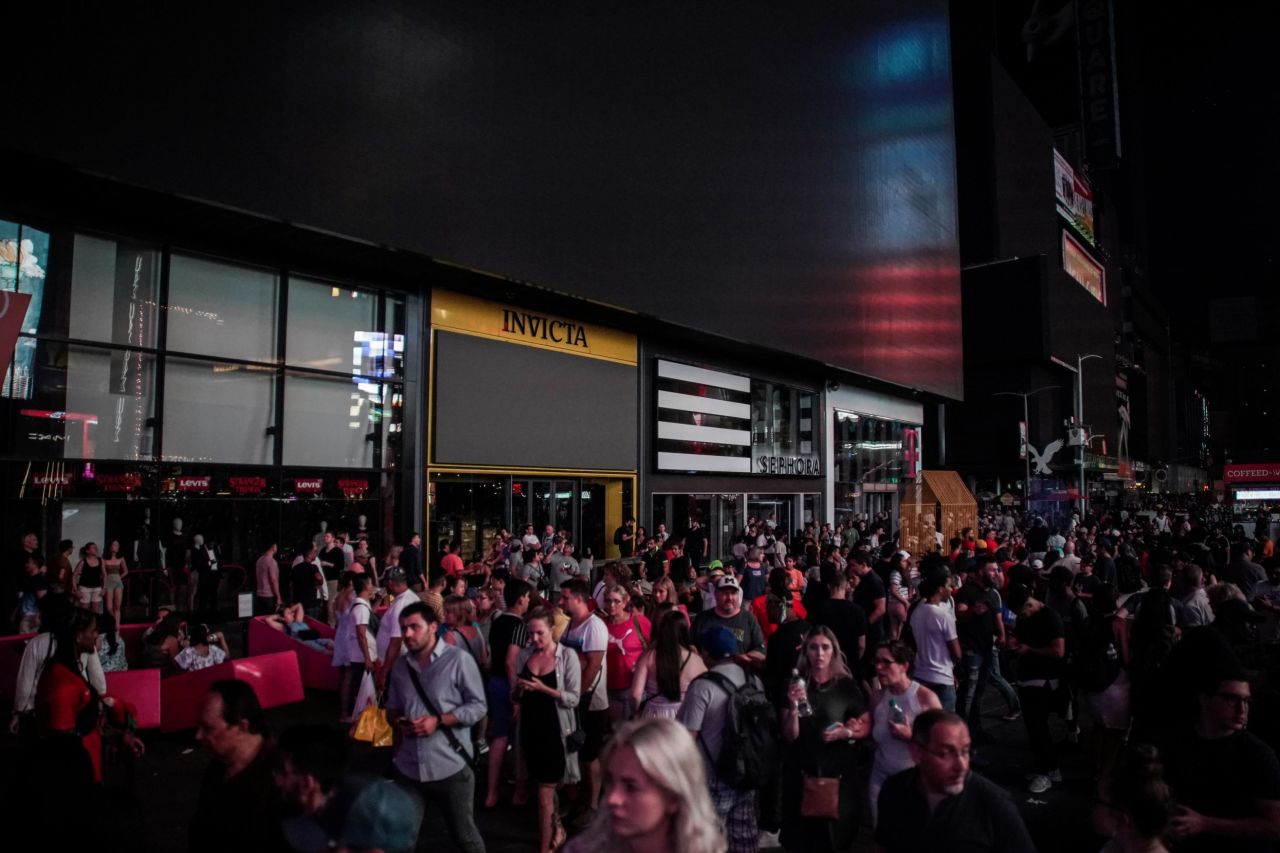 People walk along a dark street near Times Square.
