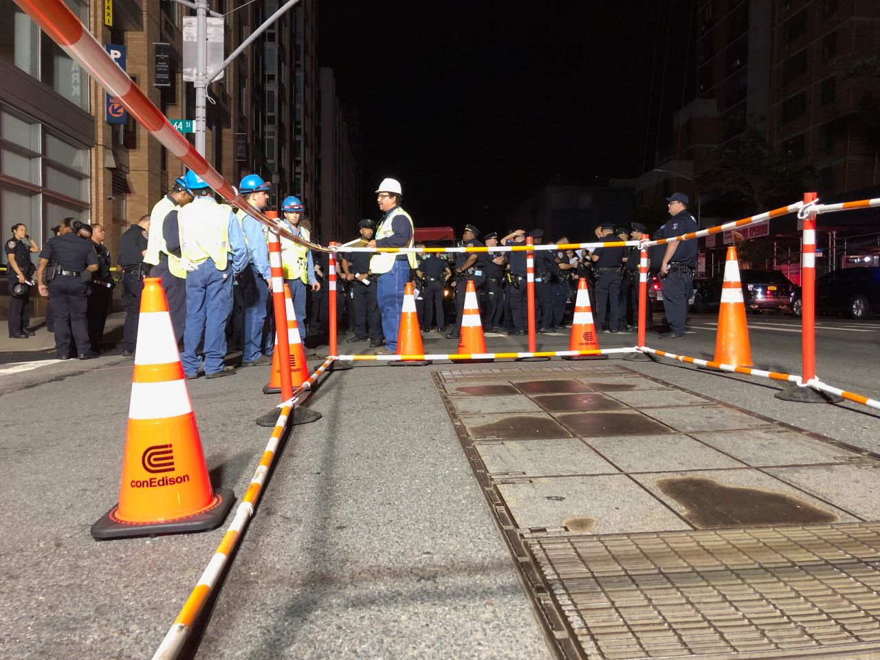 Con Edison workers stand around a barricaded transformer cover.
