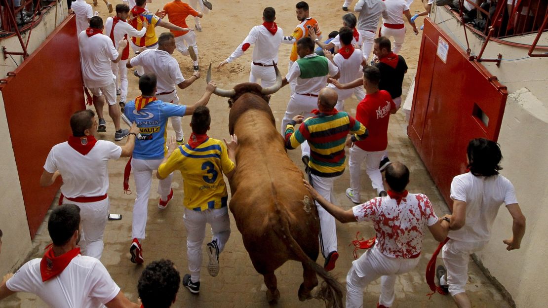 Revellers and a fighting bull face off in the bullring during the final running of the bulls at the San Fermin Festival Sunday.