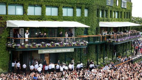 Novak Djokovic lifts the trophy as a crowd assembles at Wimbledon. 