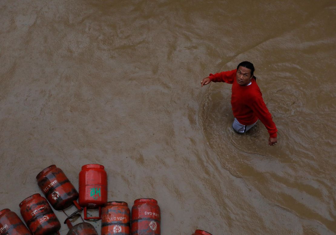 A man walks past gas cylinders in a flooded colony in Kathmandu, Nepal on July 12, 2019. 