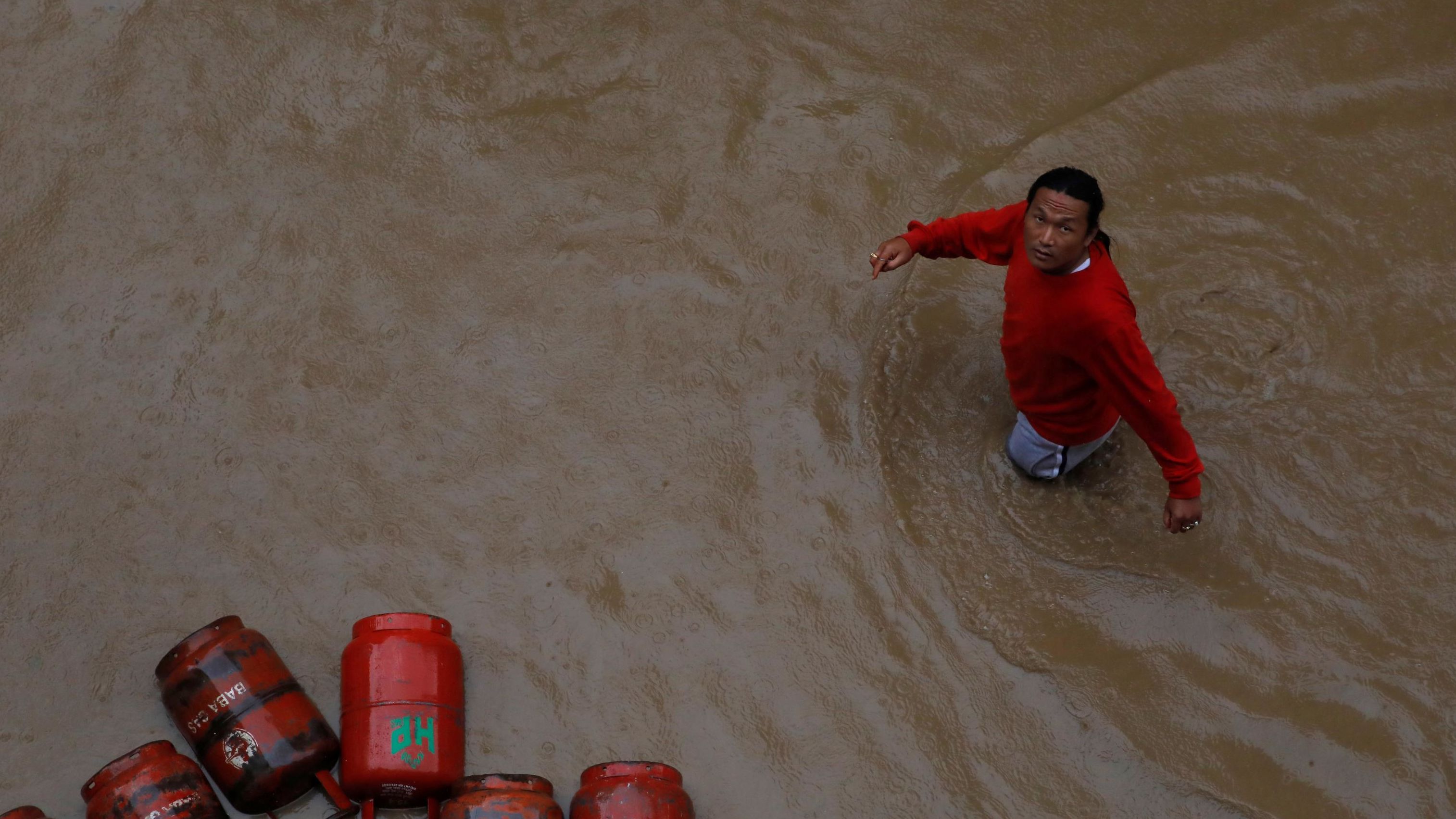 A man walks past gas cylinders in a flooded colony in Kathmandu, Nepal on July 12, 2019. 