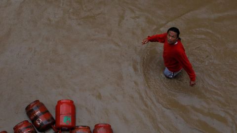A man walks past gas cylinders in a flooded colony in Kathmandu, Nepal on July 12, 2019.