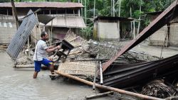An Indian woman searches her belongings near the debris of her house following floodwaters in Kasuarbori village, in the Indias northeastern state of Assam, on July 13, 2019. - At least 17 people have been killed across Nepal after torrential monsoon rains induced floods and landslides, officials said on July 12.