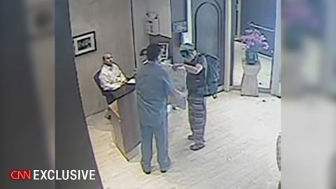An Ecuadorian security guard, who abandoned his post, receives a package outside the embassy from a man in disguise on July 18, 2016. The man covered his face with a mask and sunglasses and was wearing a backpack.
