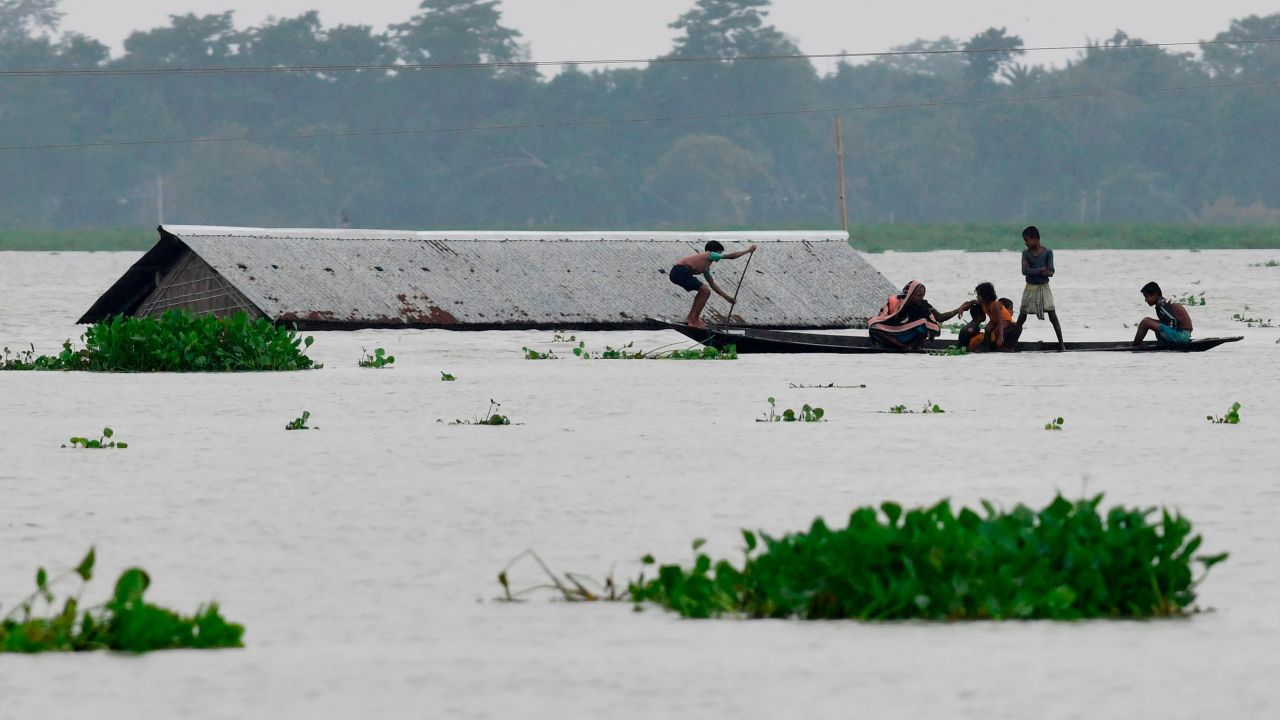 Villagers travel on a boat near a submerged house in the Morigaon district of India's Assam state on July 15, 2019.