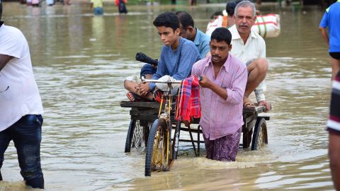 An Indian rickshaw puller transports commuters on a flooded street in the Indian state of Tripura, on July 14, 2019.