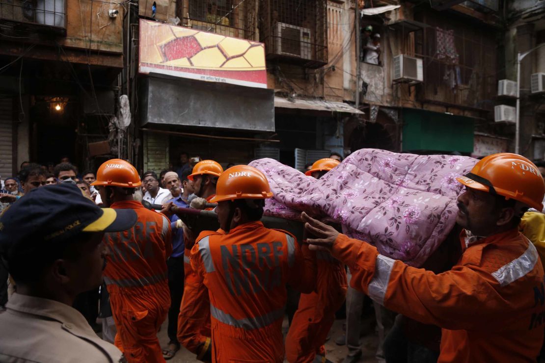 Rescuers carry the body of a victim at the scene in a crowded neighborhood of Mumbai.