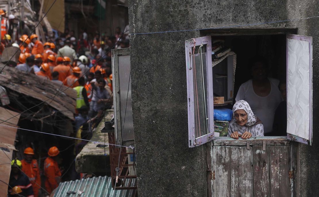 A woman watches from a window as rescuers work at the site of the collapse.