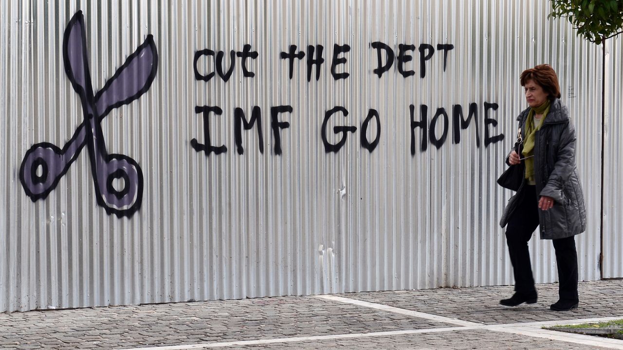 A woman walks past a slogan in central Athens in 2015 protesting the IMF bailout program that led to years of tough austerity measures.