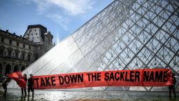 TOPSHOT - Activists of P.A.I.N. (Prescription Addiction Intervention Now) association - created to respond to the opioid crisis - and of French NGO Aides hold a banner reading "Take down the Sackler name" in front of the Pyramid of the Louvre museum (Pyramide du Louvre), on July 1, 2019 in Paris, during a protest to condemn the museum's ties with the Sackler family, billionaire donors accused of pushing to sell a highly addictive painkiller blamed for tens of thousands of deaths. - The Sacklers have been high-profile philanthropists to cultural institutions such as the Tate in London and the Guggenheim in New York, but museums and galleries have recently been rebuffing their donations because of the opioid crisis fallout. The most recent museum to cut ties with the Sackler family is New York's Metropolitan Museum, which announced earlier this month that it will cease accepting gifts from the family. The Louvre Pyramid was designed by Chinese-born US architect Ieoh Ming Pei. (Photo by STEPHANE DE SAKUTIN / AFP)        (Photo credit should read STEPHANE DE SAKUTIN/AFP/Getty Images)