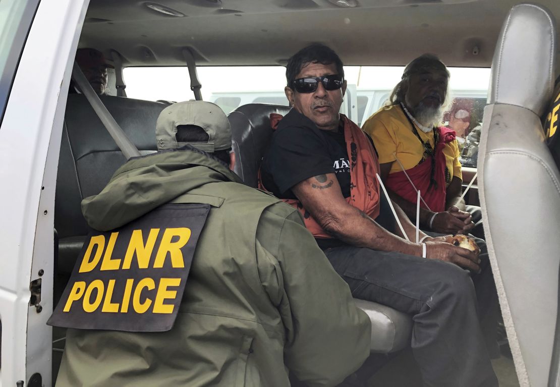 Officers from the Hawaii Department of Land and Natural Resources arrest protesters, many of them elderly.