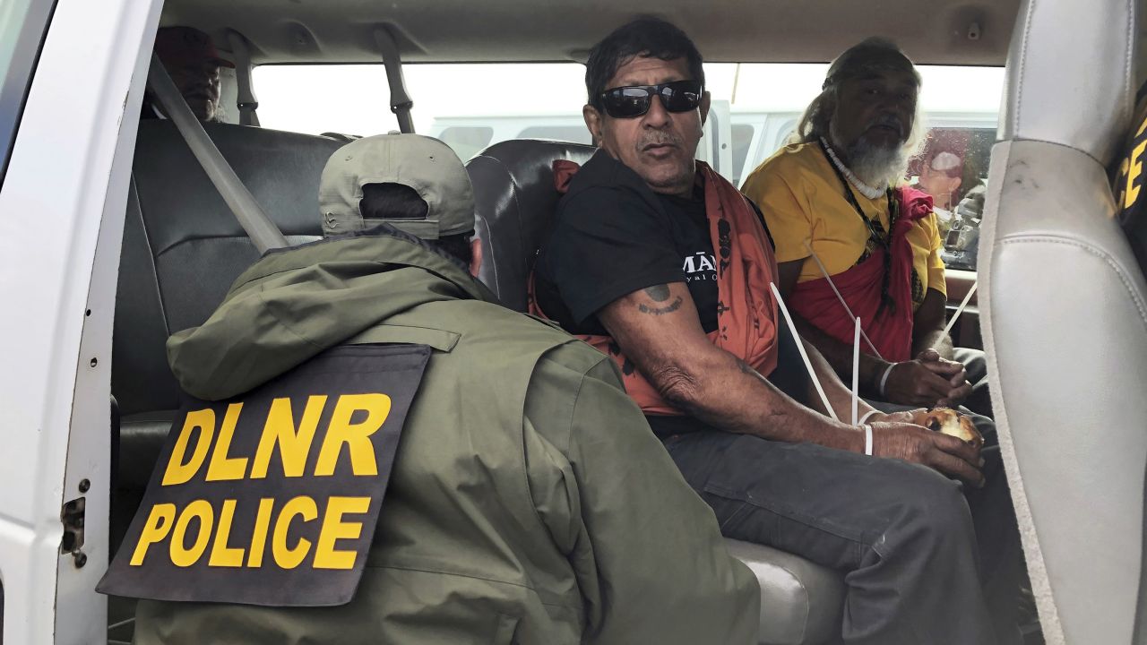 Officers from the Hawaii Department of Land and Natural Resources arrest protesters, many of them elderly.