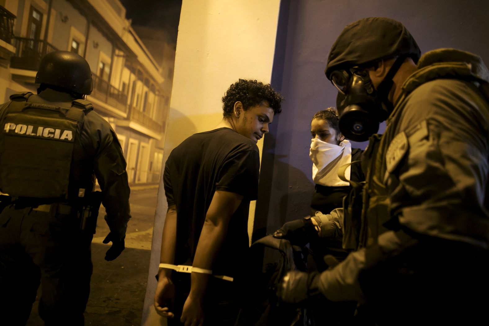 Police officers search the bag of a detained demonstrator on July 17.