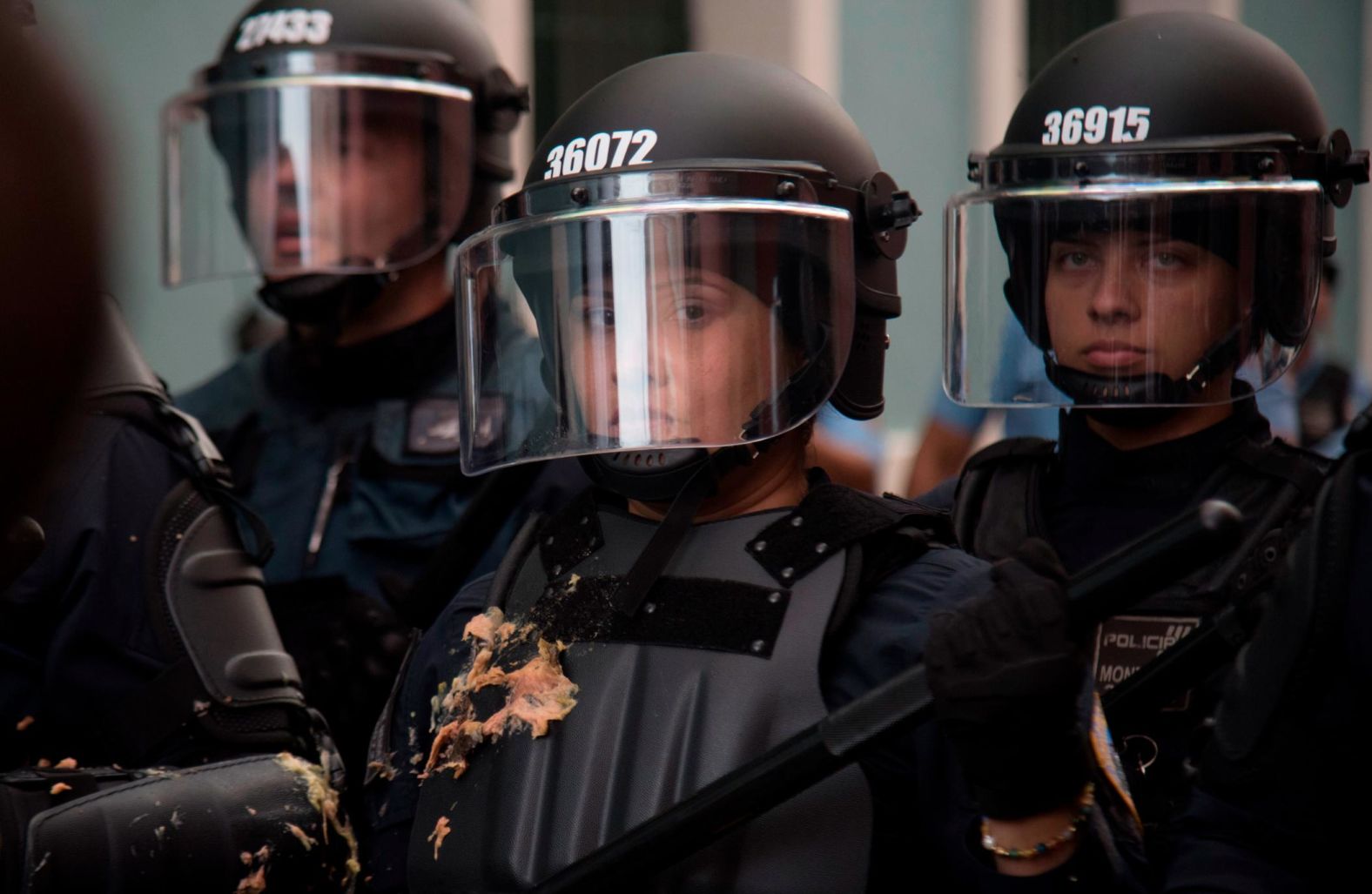 A police officer blocks protesters from reaching the governor's residence on Sunday, July 14.