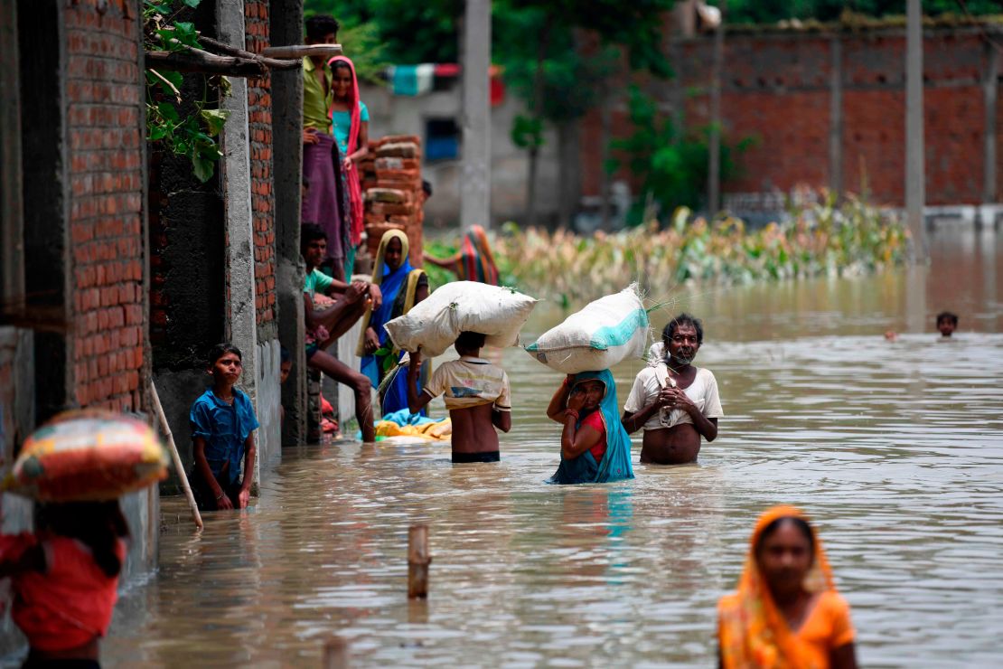 Indian residents in the state of Bihar wade along a flooded street carrying their belongings on July 17, 2019.