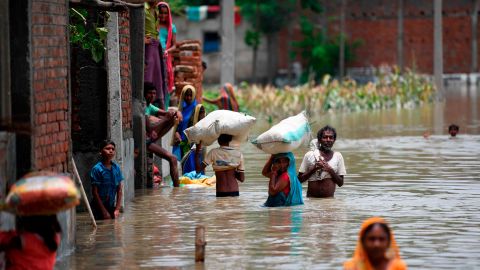 Indian residents in the state of Bihar wade along a flooded street carrying their belongings on July 17, 2019.