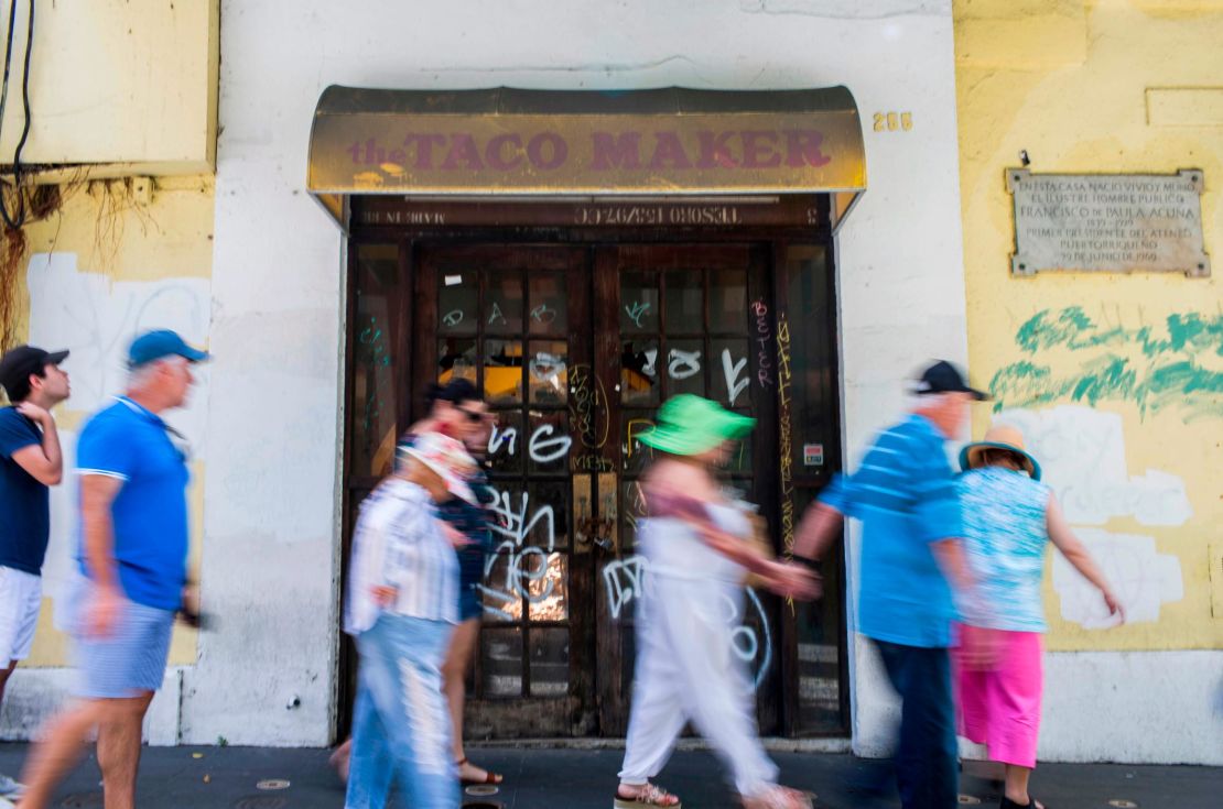 Tourists walk past a closed taco restaurant in San Juan.