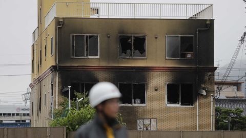 A security guard stands near the destroyed Kyoto Animation Studio building.