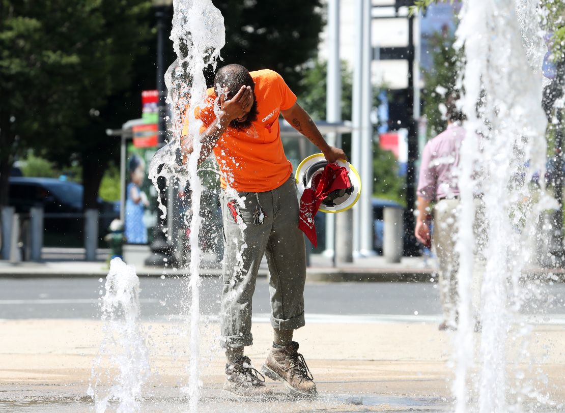 A construction worker stops to cool off in the water fountains at Canal Park in Washington.