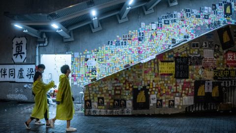 People walk in front of a so-called "Lennon Wall" where messages of support have been left for anti-extradition bill protesters on July 1, 2019 in Hong Kong.