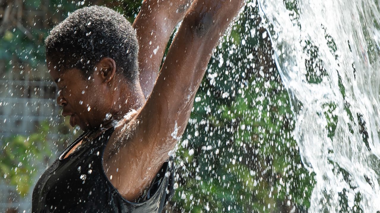 A woman cools down in a waterfall at Yards Park in Washington, DC, July 19, 2019, as an extreme heat wave hits the region. - Some 100 heat records are expected to fall this weekend, according to the National Weather Service, as a heat wave hits the midwest and eastern US. (Photo by SAUL LOEB / AFP)        (Photo credit should read SAUL LOEB/AFP/Getty Images)